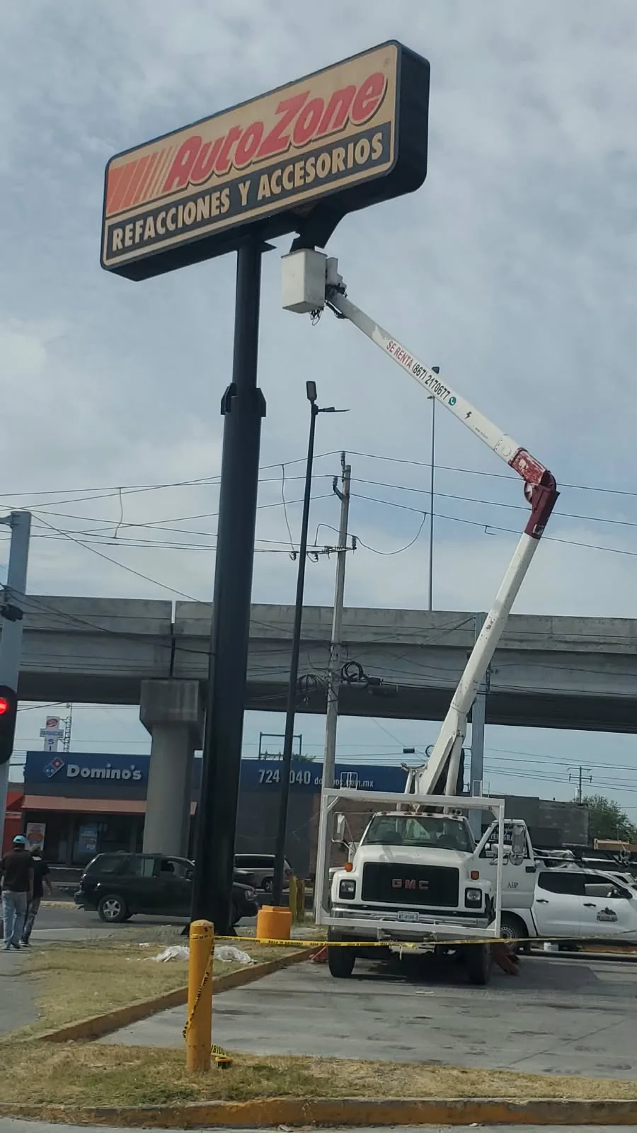 Servicio al anuncio de pilón de AutoZone sobre avenida, con canastilla