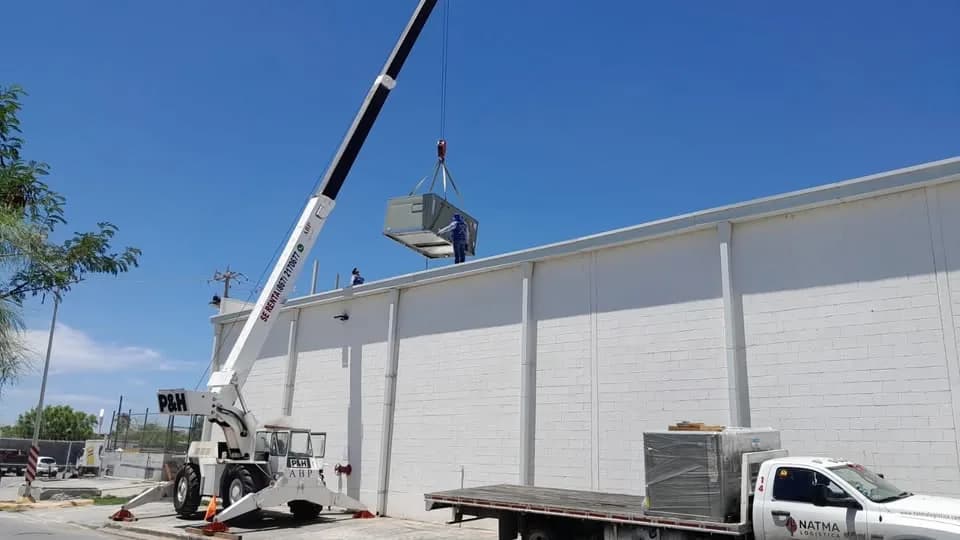 Subida de una unidad de aire acondicionado a la azotea de una nave